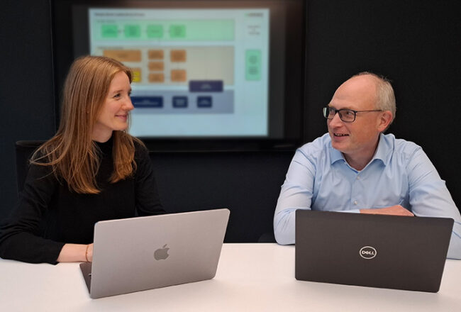 Merle Rüter und Stefan Meyer im Arbeitsmeeting mit Notebooks vor Prozesschart